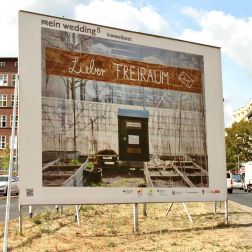 Ein Foto der Plakatwand auf der Müllerstraße, auf dem das Motiv "Lieber Freiraum" zu sehen ist: Ein Holzschild mit der Aufschrift "Lieber Freiraum", darunter ein Briefkasten mit himmelbeet-Logo & handgeschriebenem Zettel auf dem steht: "keine Werbung"