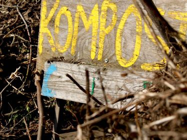 Nahaufnahme von Kompost und dem Hinweisschild mit der Aufschrift Kompost