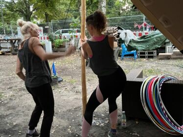 Zwei Menschen machen Stretching in Vorbereitung auf dem Hula-Hoop Workshop